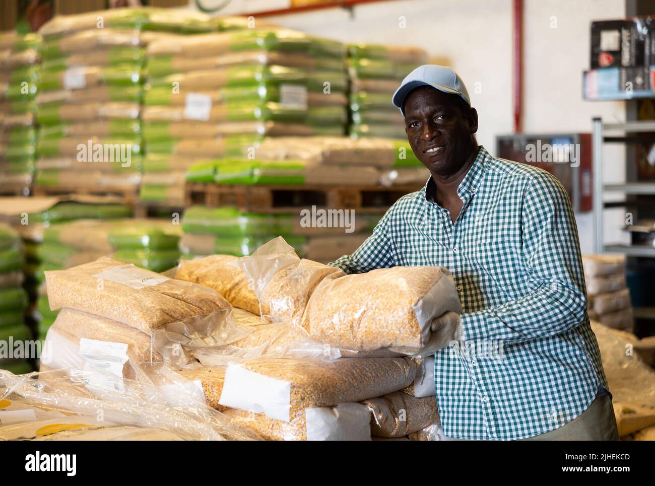 Man working in warehouse, carrying bag full of corn seeds Stock Photo