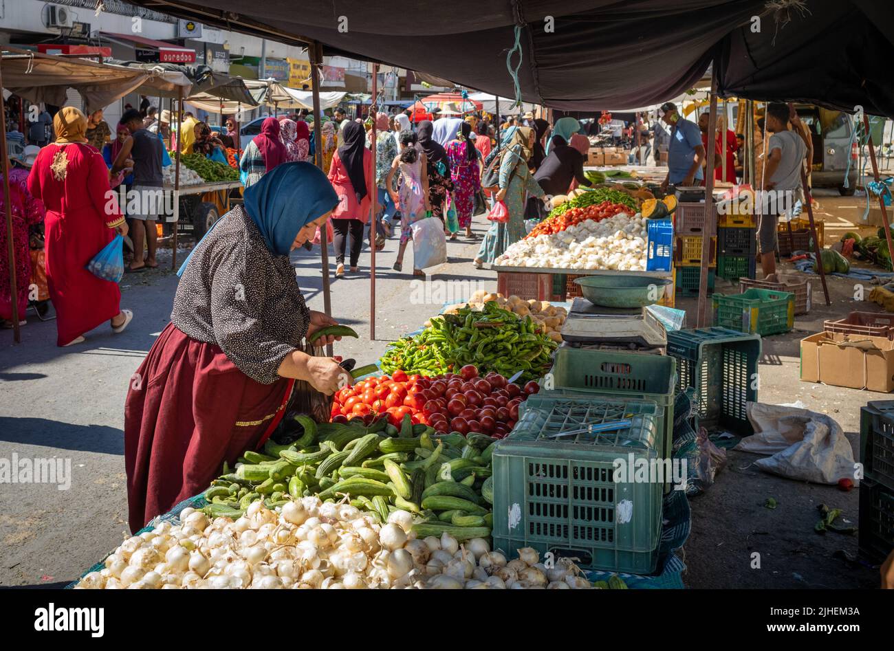 A woman buys vegetables at a stall at the Sunday Souk, a weekly market in Sousse, Tunisia. Stock Photo
