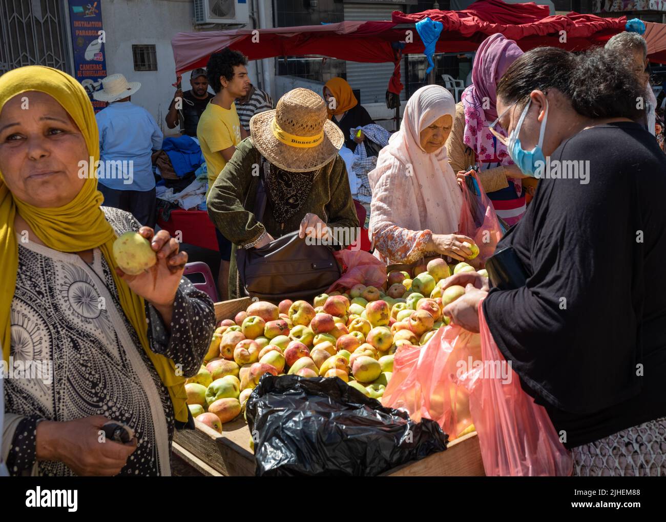 Women buy apples at a fruit stall at the Sunday Souk, a weekly market in Sousse, Tunisia.x Stock Photo