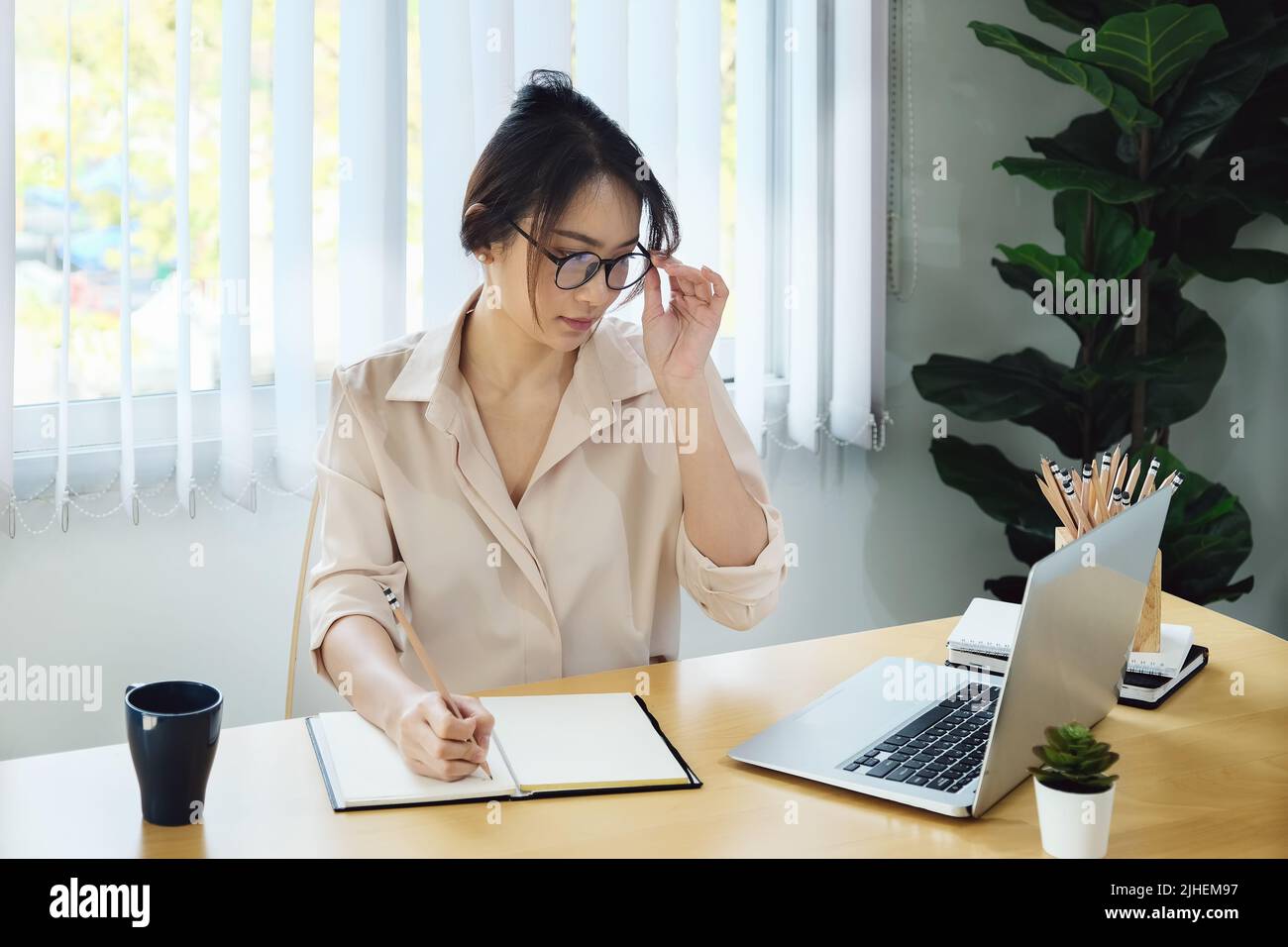 new normal, a businesswoman uses a computer to work for a company Via the internet on your desk at home. Stock Photo