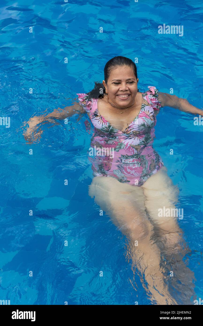 Older woman relaxing in the pool during the summer. Stock Photo