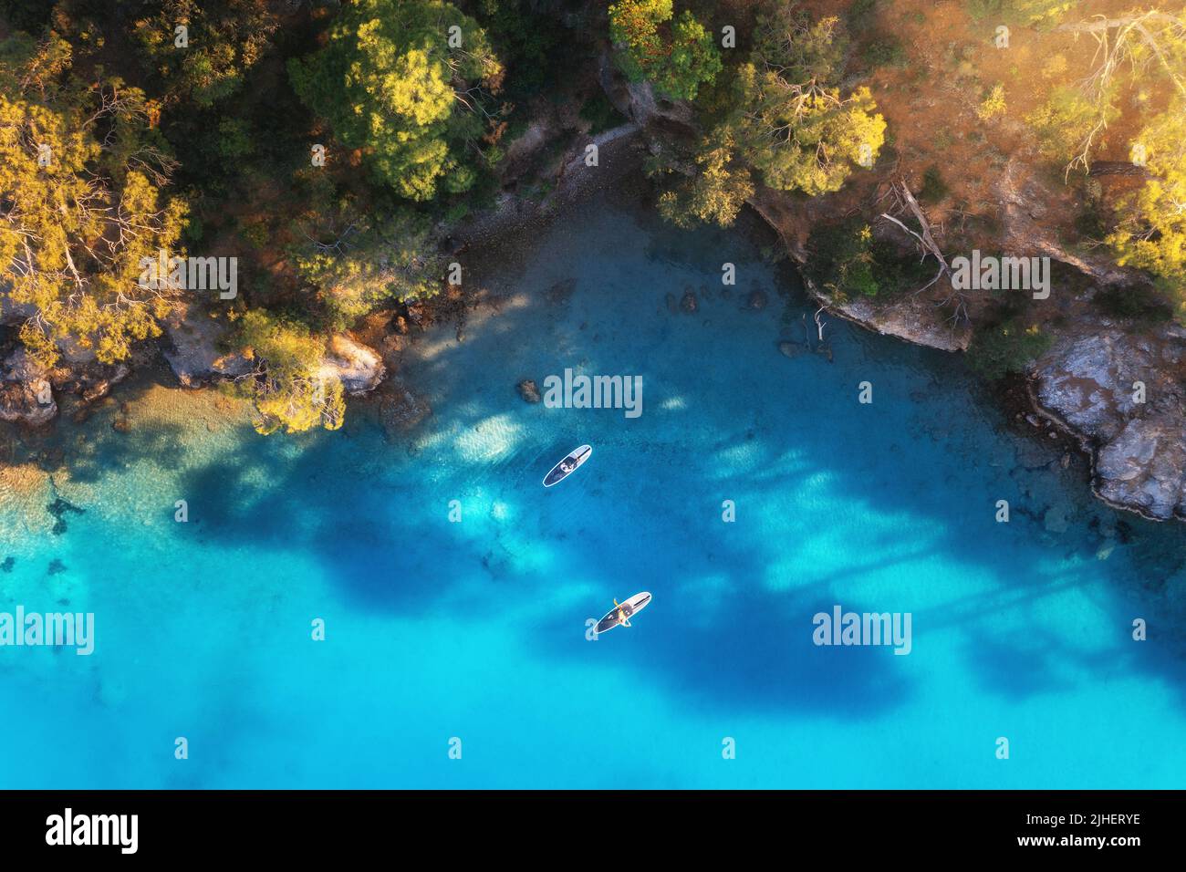 Aerial view of floating board and people on blue sea, rocks Stock Photo
