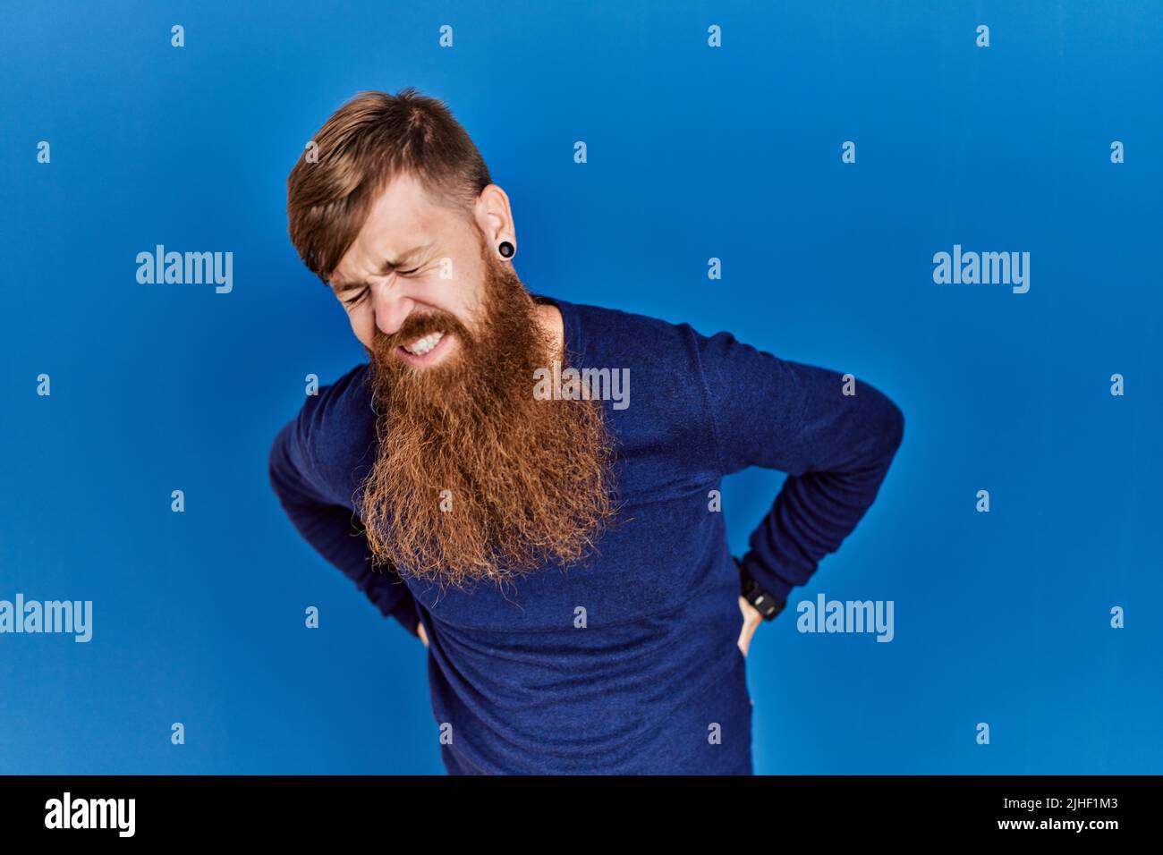Redhead man with long beard wearing casual blue sweater over blue ...