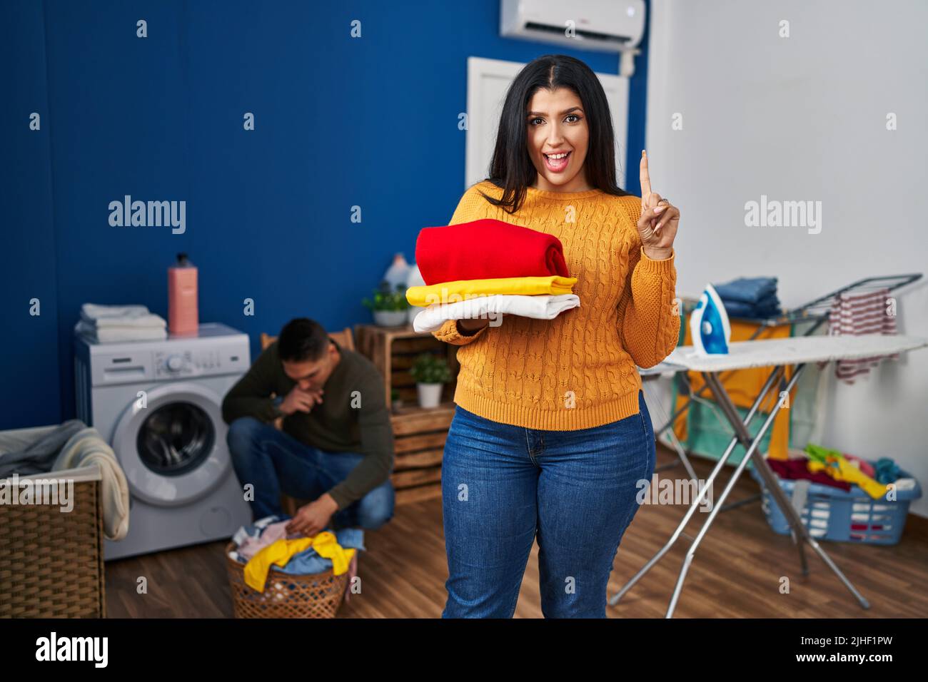 Young couple doing laundry at home smiling with an idea or question ...