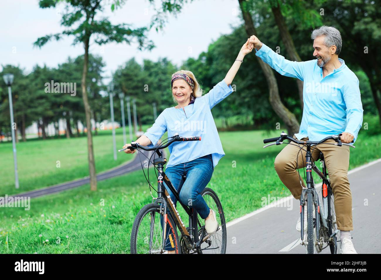 senior couple happy elderly love together retirement bicycle bike man woman mature fun Stock Photo