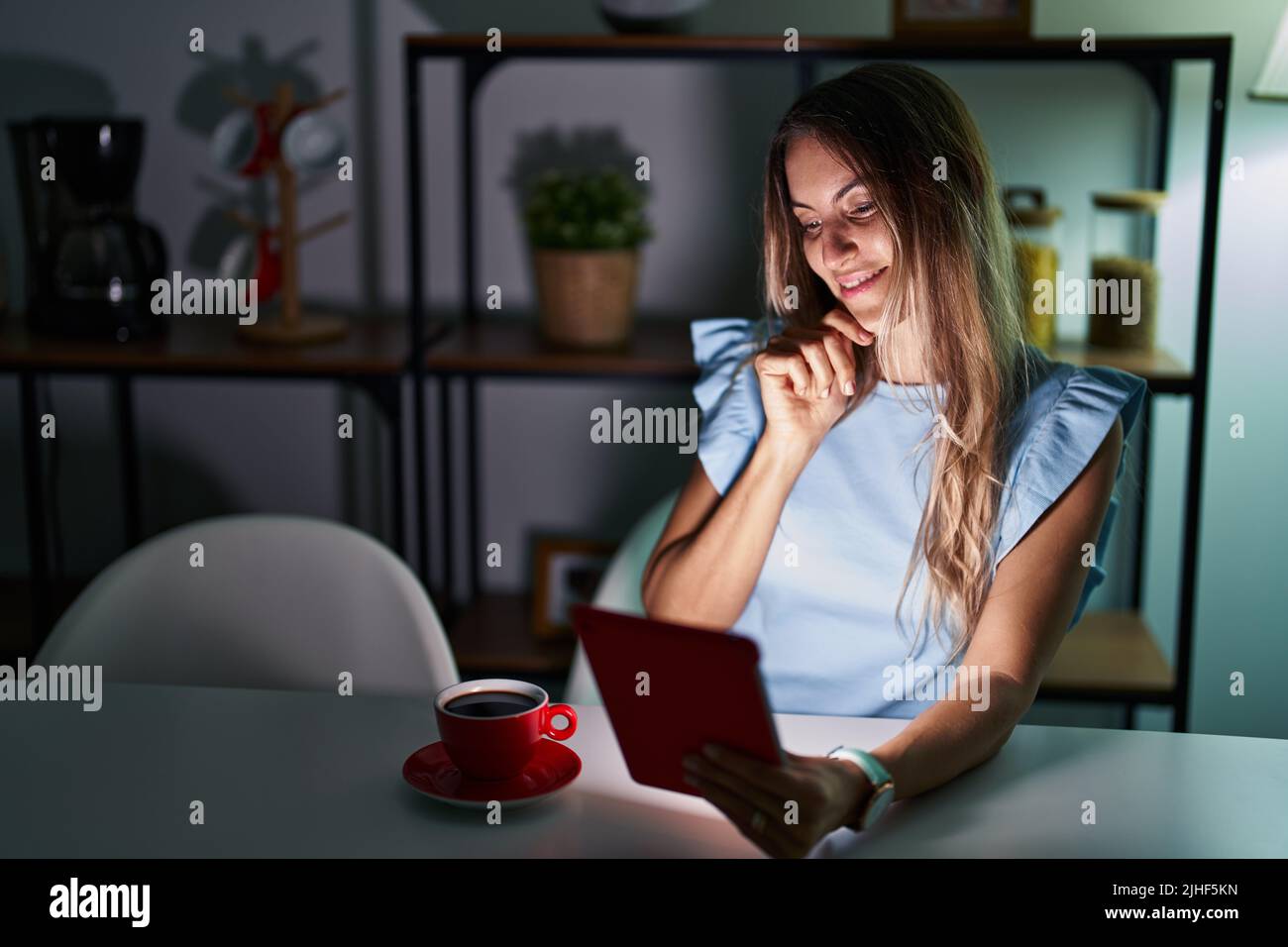 Young hispanic woman using touchpad sitting on the table at night ...