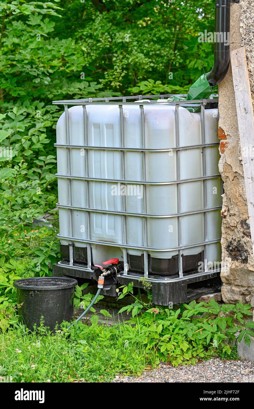 rainwater with big cubic tank with black bucket Stock Photo