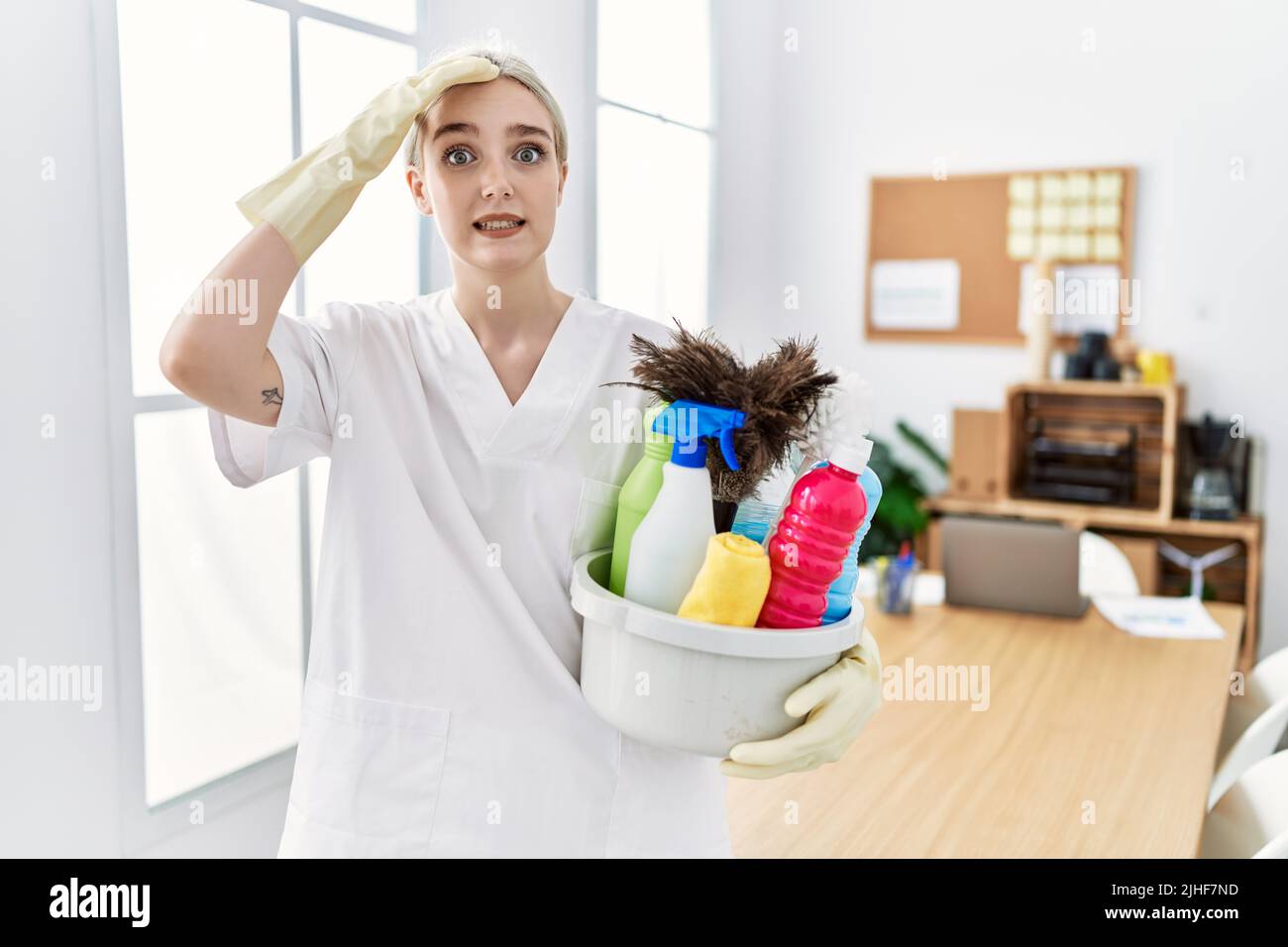 Young caucasian woman wearing cleaner uniform holding cleaning products