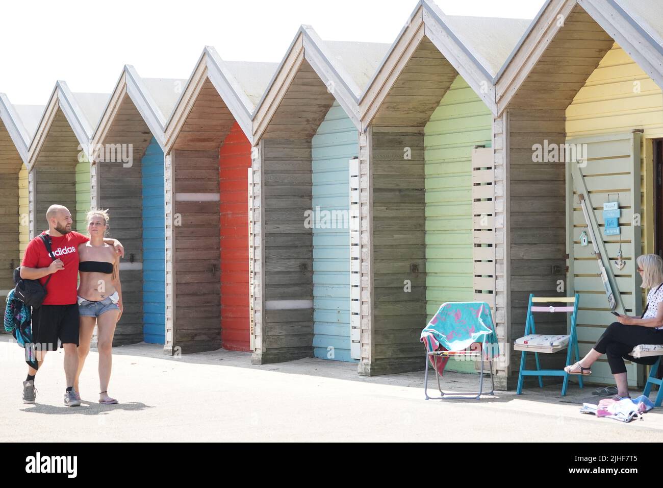 People near the beach huts on Blyth beach, Northumberland, on the north east coast, as the heatwave sweeps across England. Picture date: Monday July 18, 2022. Stock Photo