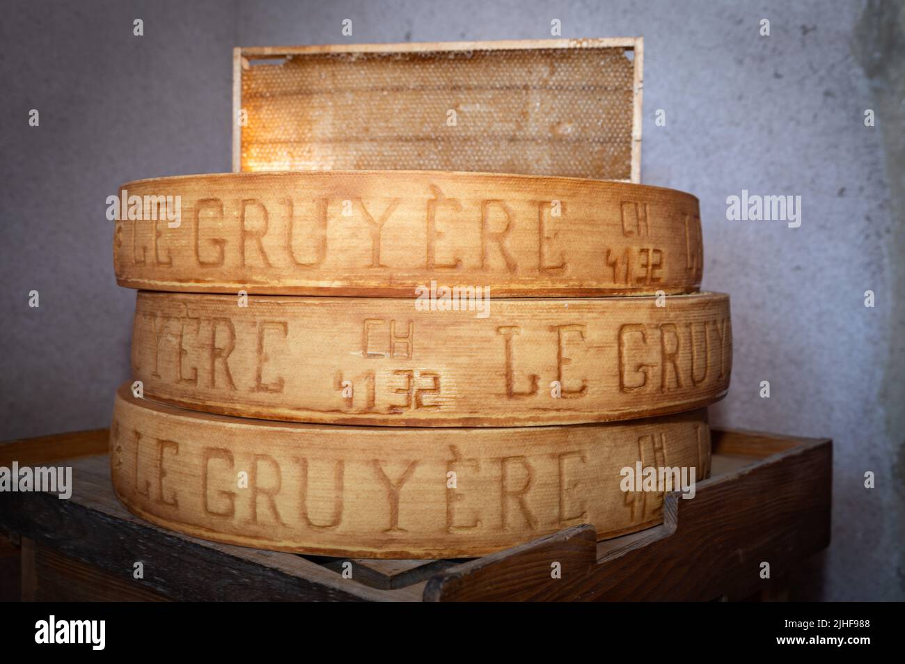 stack of wheels of Swiss Le Gruyère PDO cheese in a cellar with a honeycomb Stock Photo