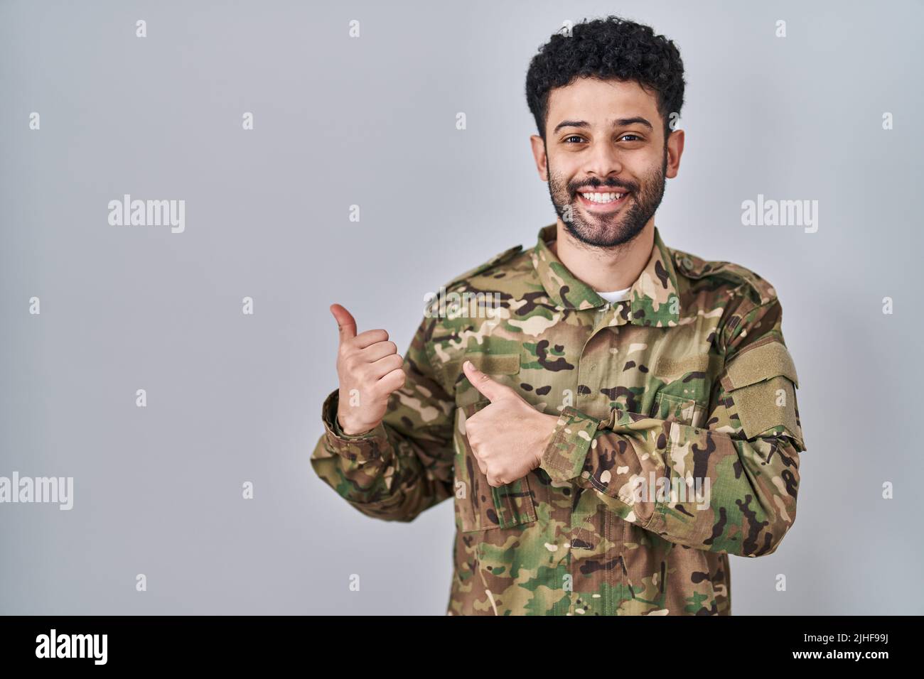Arab man wearing camouflage army uniform pointing to the back behind