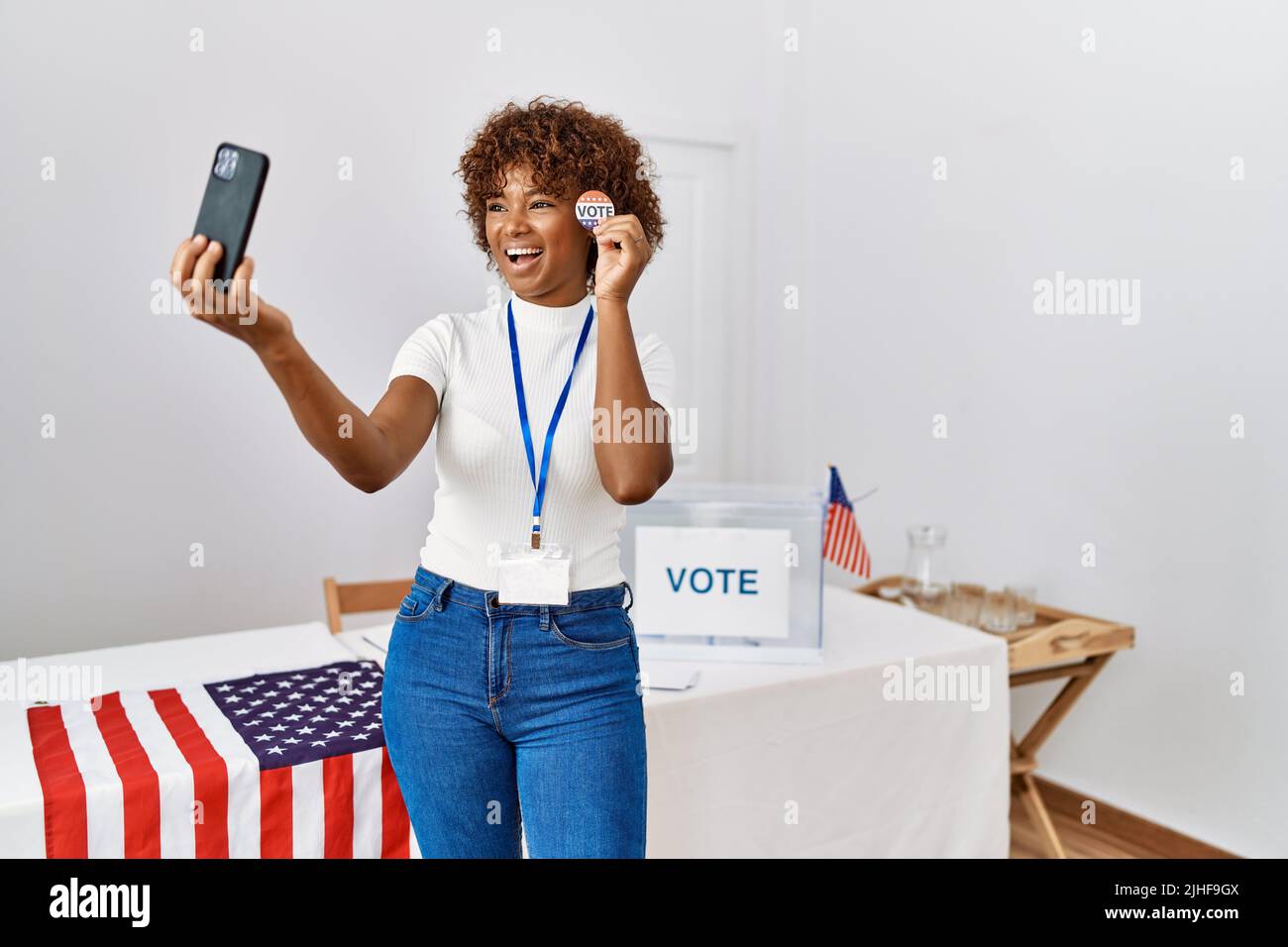 Young african american woman holding badge make selfie by the smartphone at electoral college Stock Photo