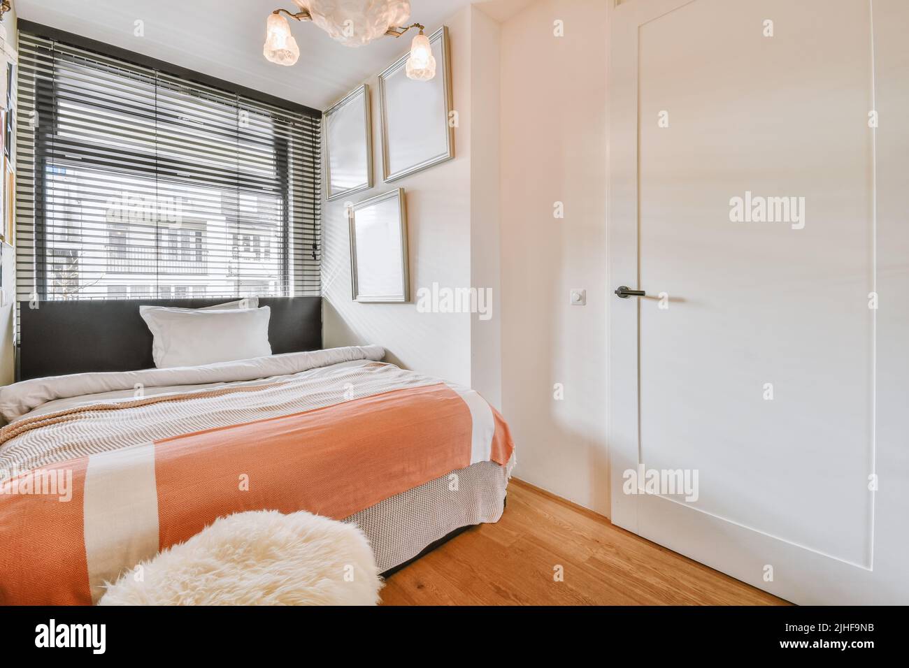 Comfortable bed located near window with curtain in light bedroom Stock Photo Alamy
