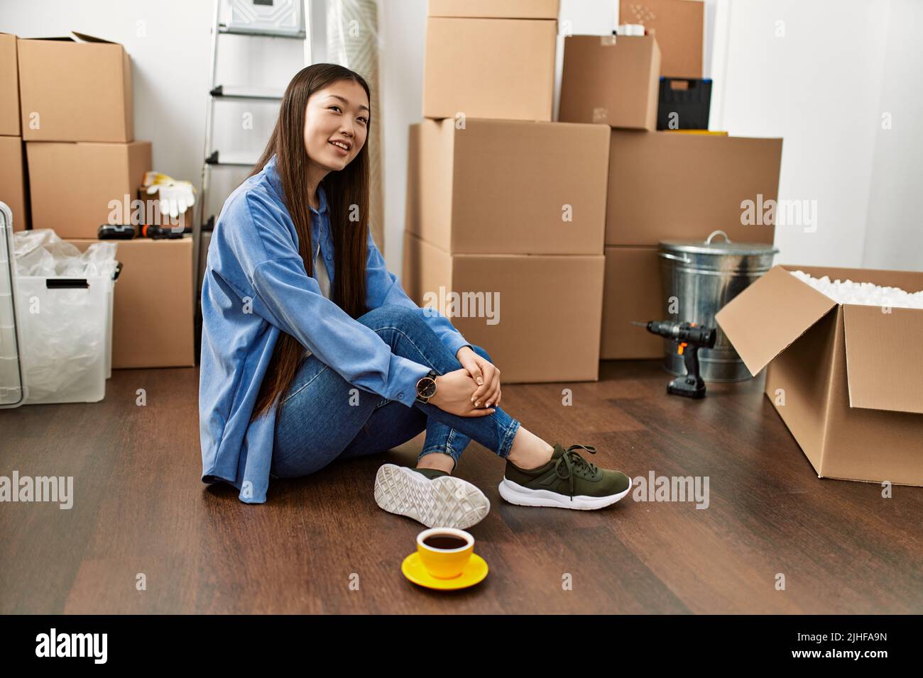 Young chinese girl smiling happy sitting on the floor at new home Stock Photo Alamy