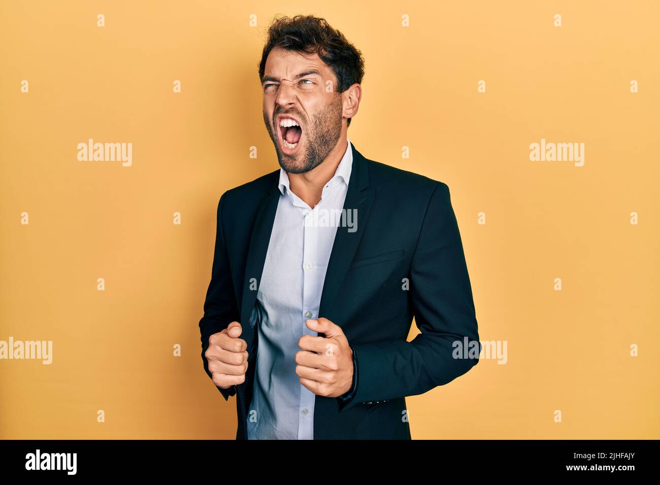 Handsome man with beard wearing business suit holding jacket angry and ...