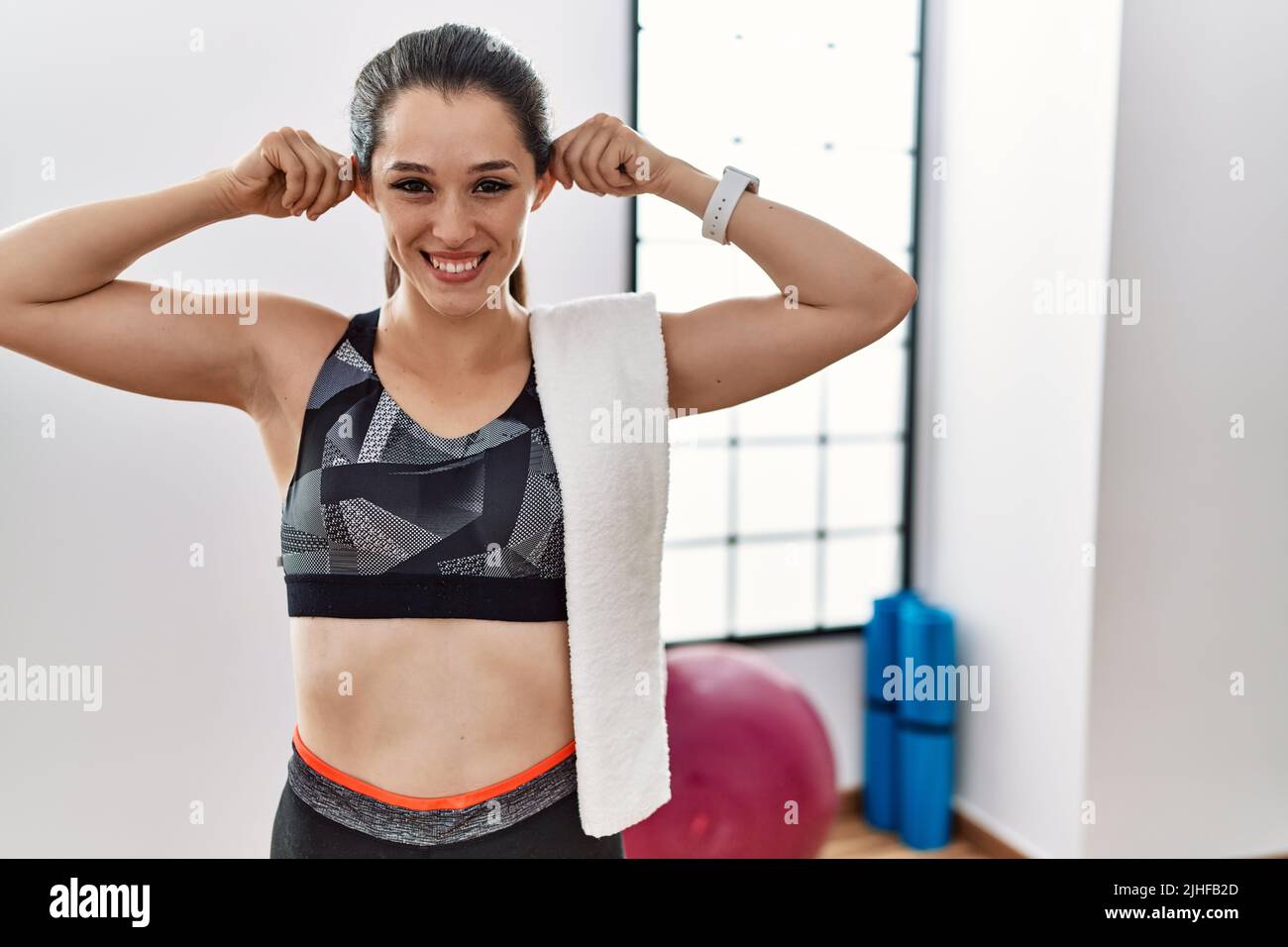 Young woman wearing sportswear and towel at the gym smiling