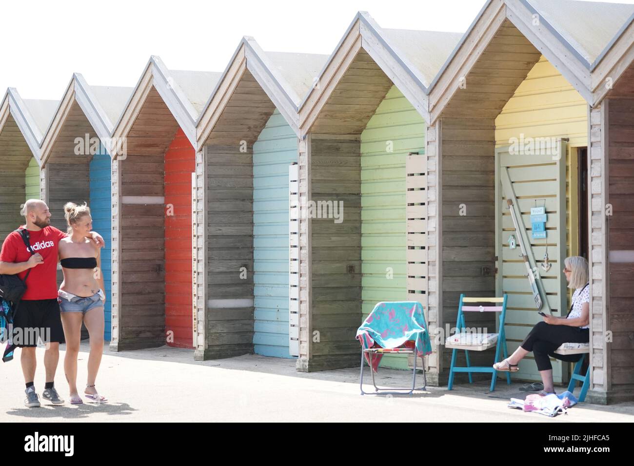 People near the beach huts on Blyth beach, Northumberland, on the north east coast, as the heatwave sweeps across England. Picture date: Monday July 18, 2022. Stock Photo