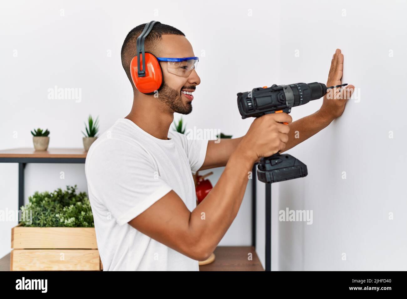 Young hispanic man smiling confident using drill at home Stock Photo