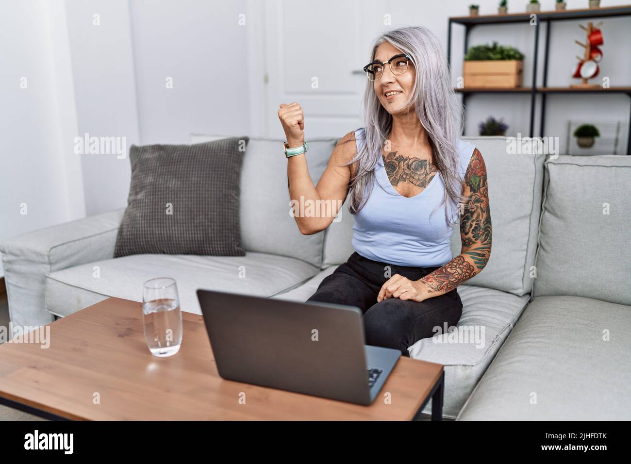 Middle age grey-haired woman using laptop at home smiling with happy ...