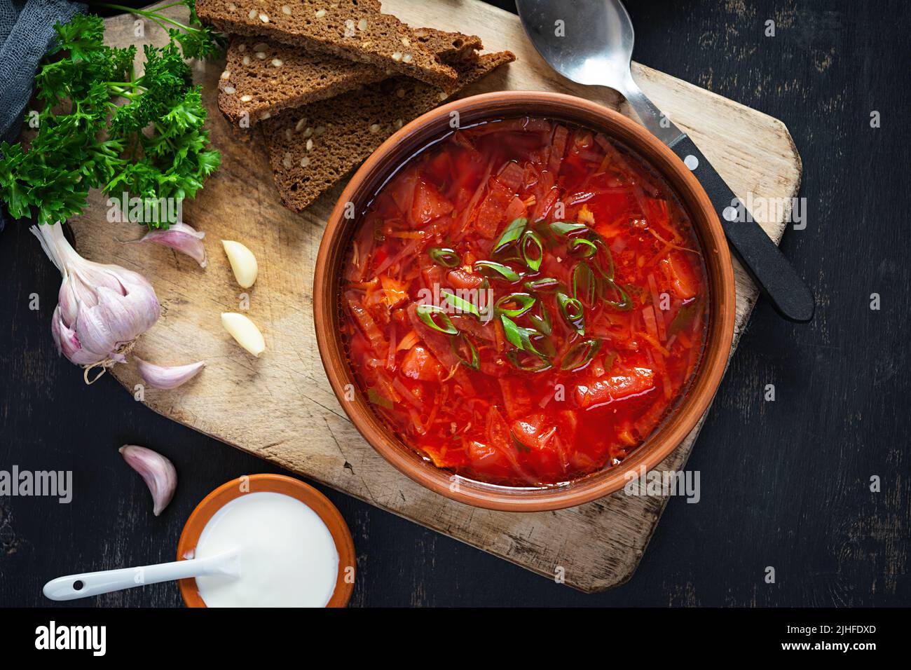 Traditional ukrainian borscht with green onion and sour cream. Delicious beet soup in bowl with rye bread. Top view Stock Photo