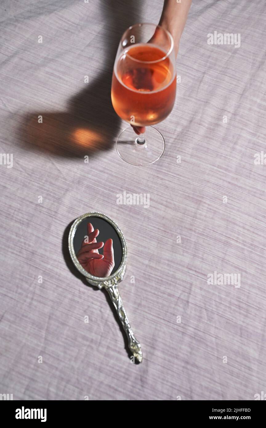 Abstract Hand in Vintage Mirror and Woman hand holding Glass of Rose Wine Stock Photo