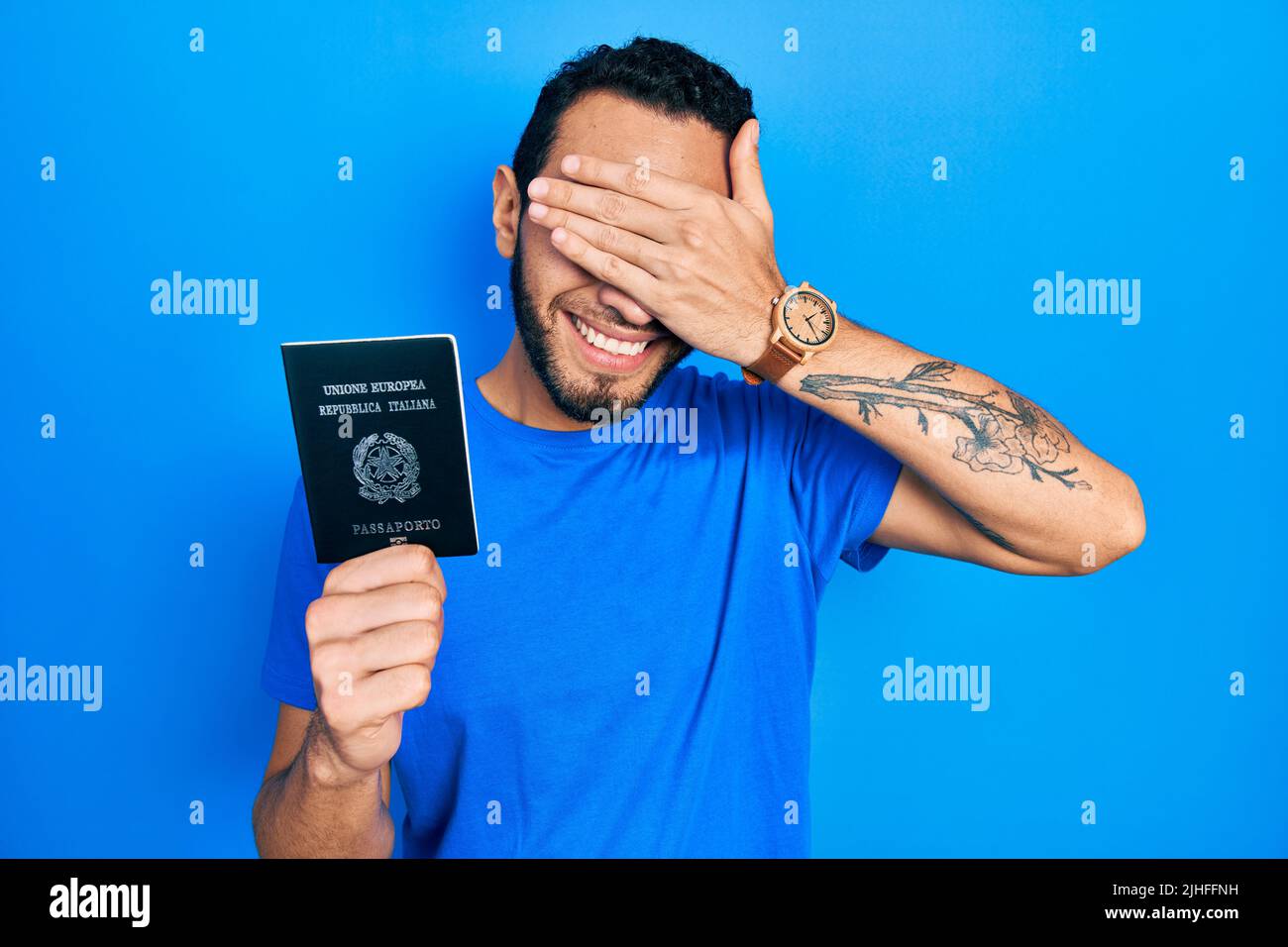 Hispanic man with beard holding italy passport smiling and laughing