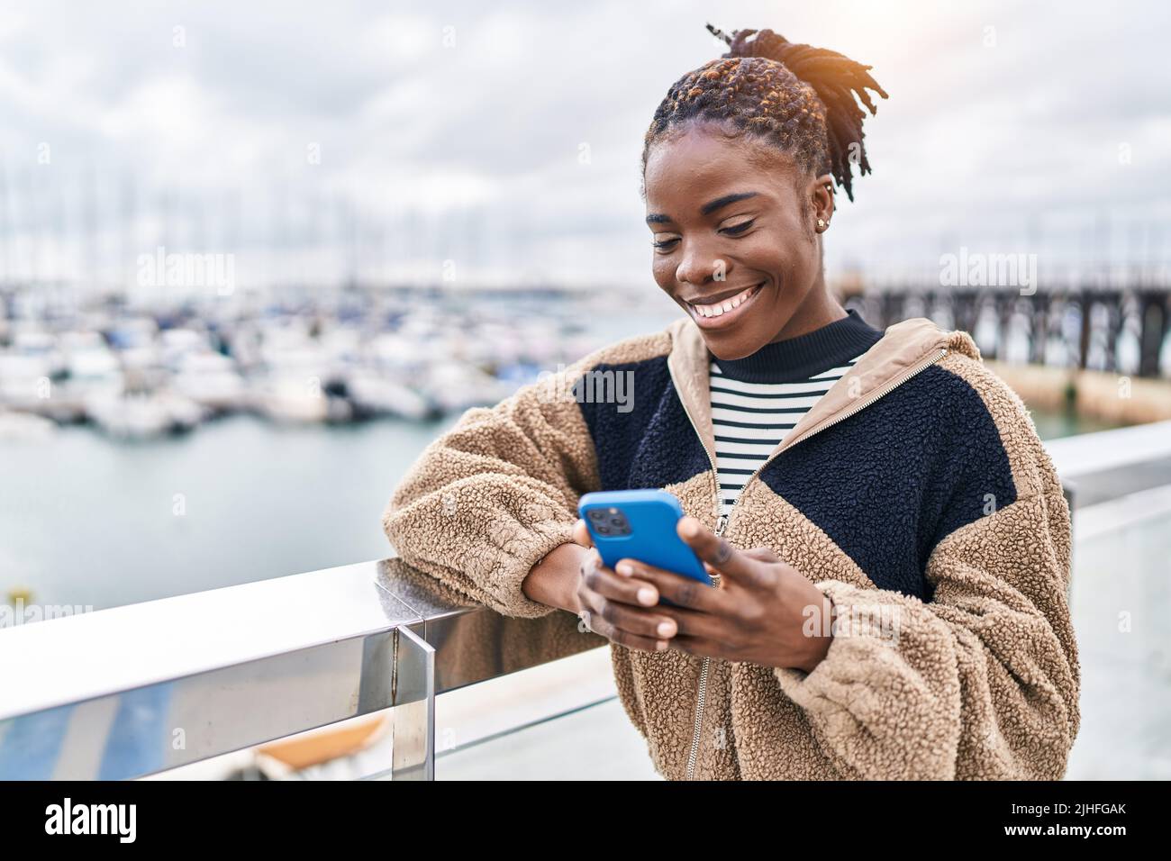 African american woman smiling confident using smartphone at seaside ...