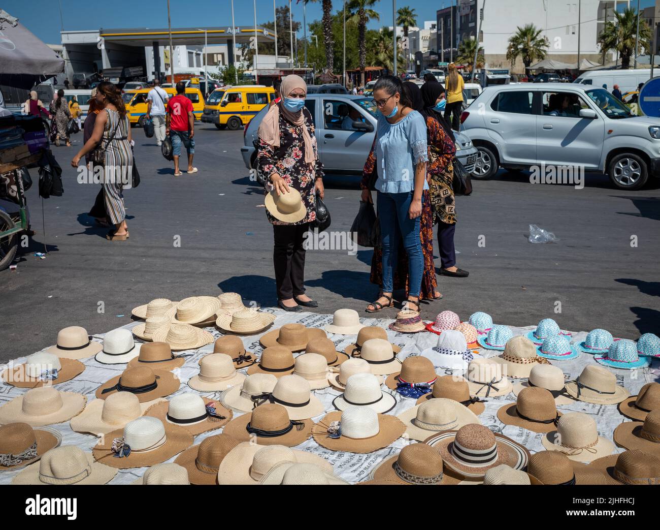 Women stop to look at a stall selling hats at the Sunday Souk, a weekly market in Sousse, Tunisia. Stock Photo