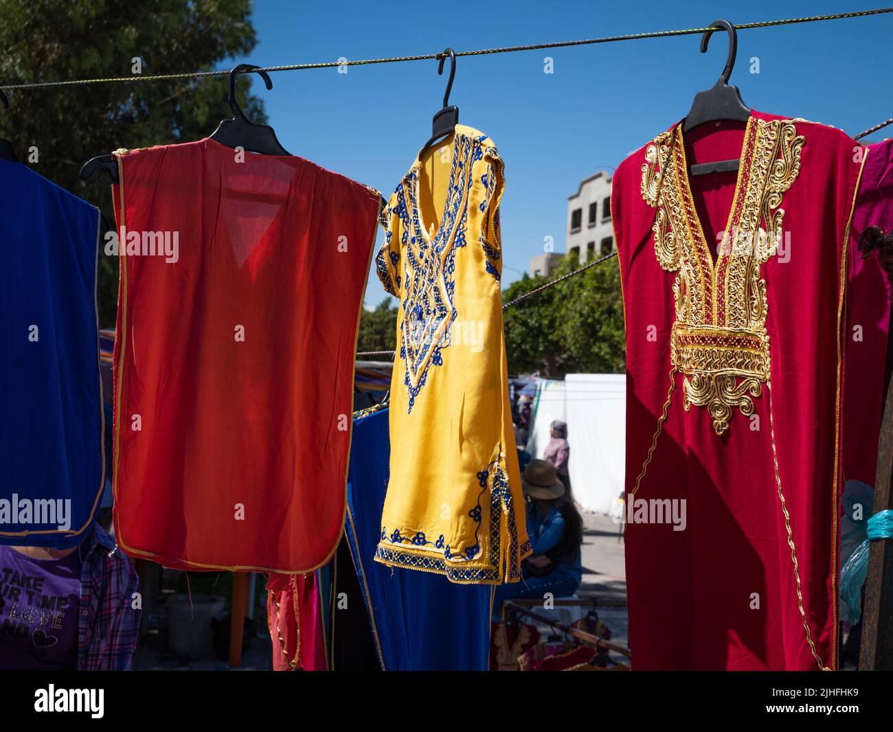 Traditional embroidered women's dresses for sale in the Sunday Souk, a weekly market in Sousse, Tunisia. Stock Photo