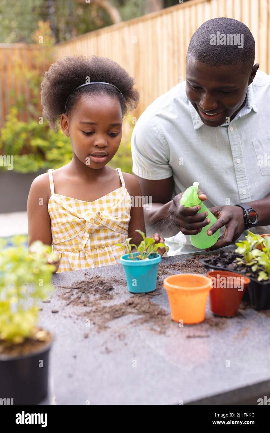 Vertical image of happy african american father and daughter gardening together Stock Photo