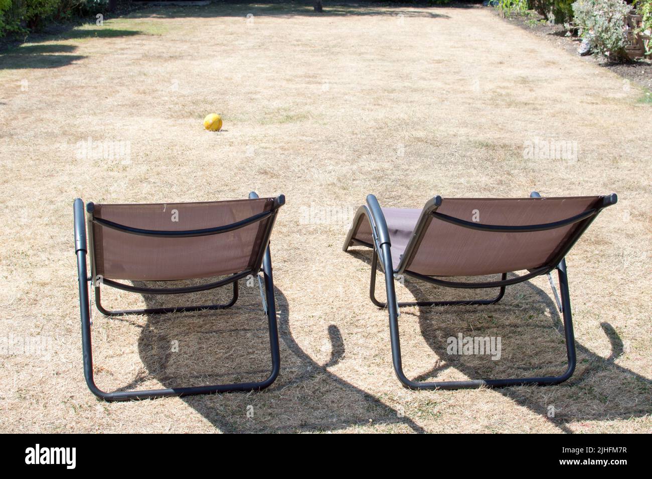 Home deck chairs on dry grass lawn during heatwave 2022 Stock Photo