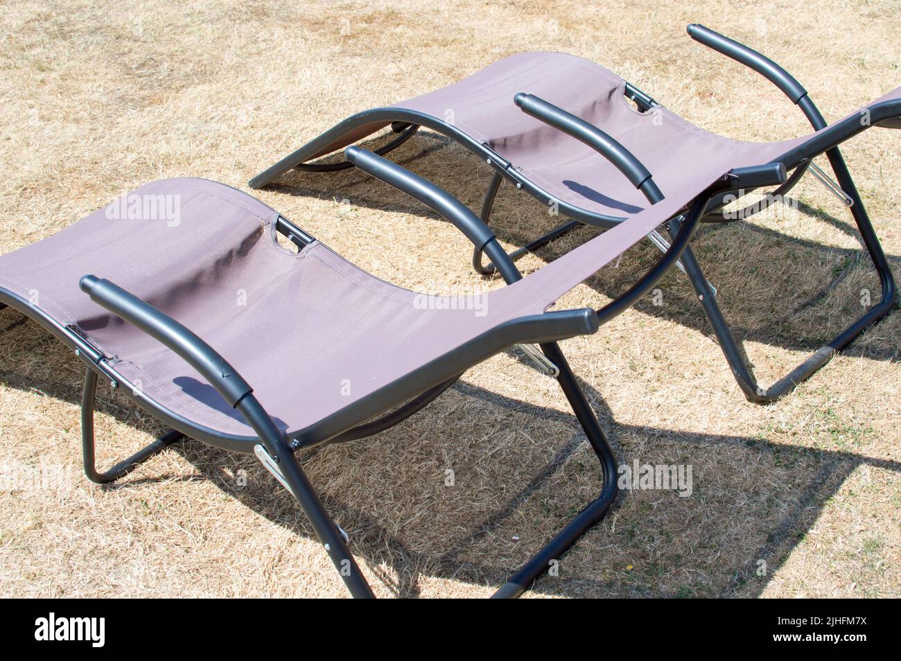 Home deck chairs on dry grass lawn during heatwave 2022 Stock Photo