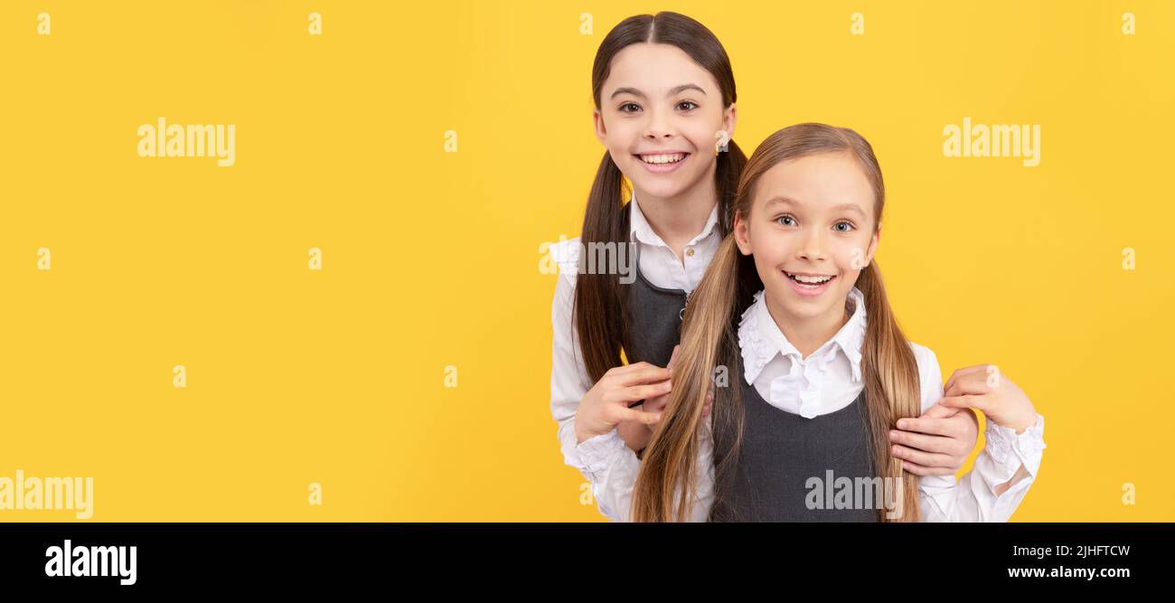 School girls friends. Happy school kids with beauty look wear long hair in formal uniforms yellow background. Portrait of schoolgirl student, studio Stock Photo