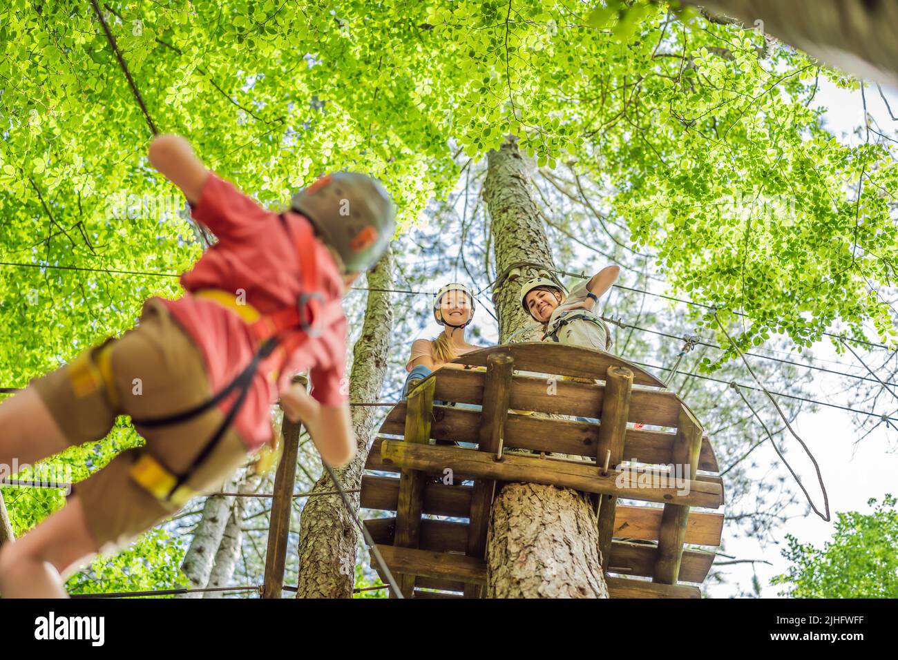 Friends on the ropes course. Young people in safety equipment are ...