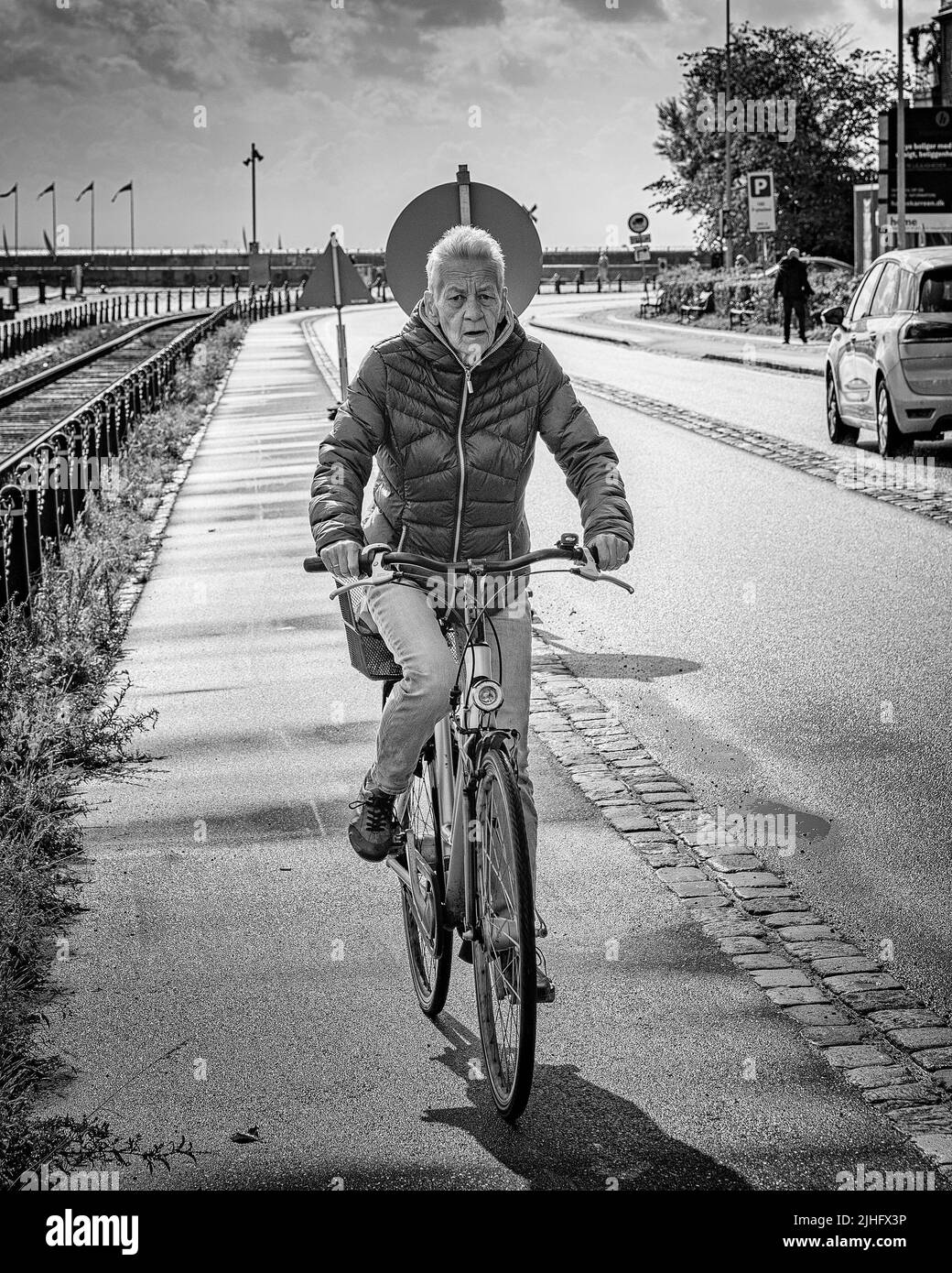 A female pensioner cycling around the city streets on her bike in Helsingor, Denmark Stock Photo
