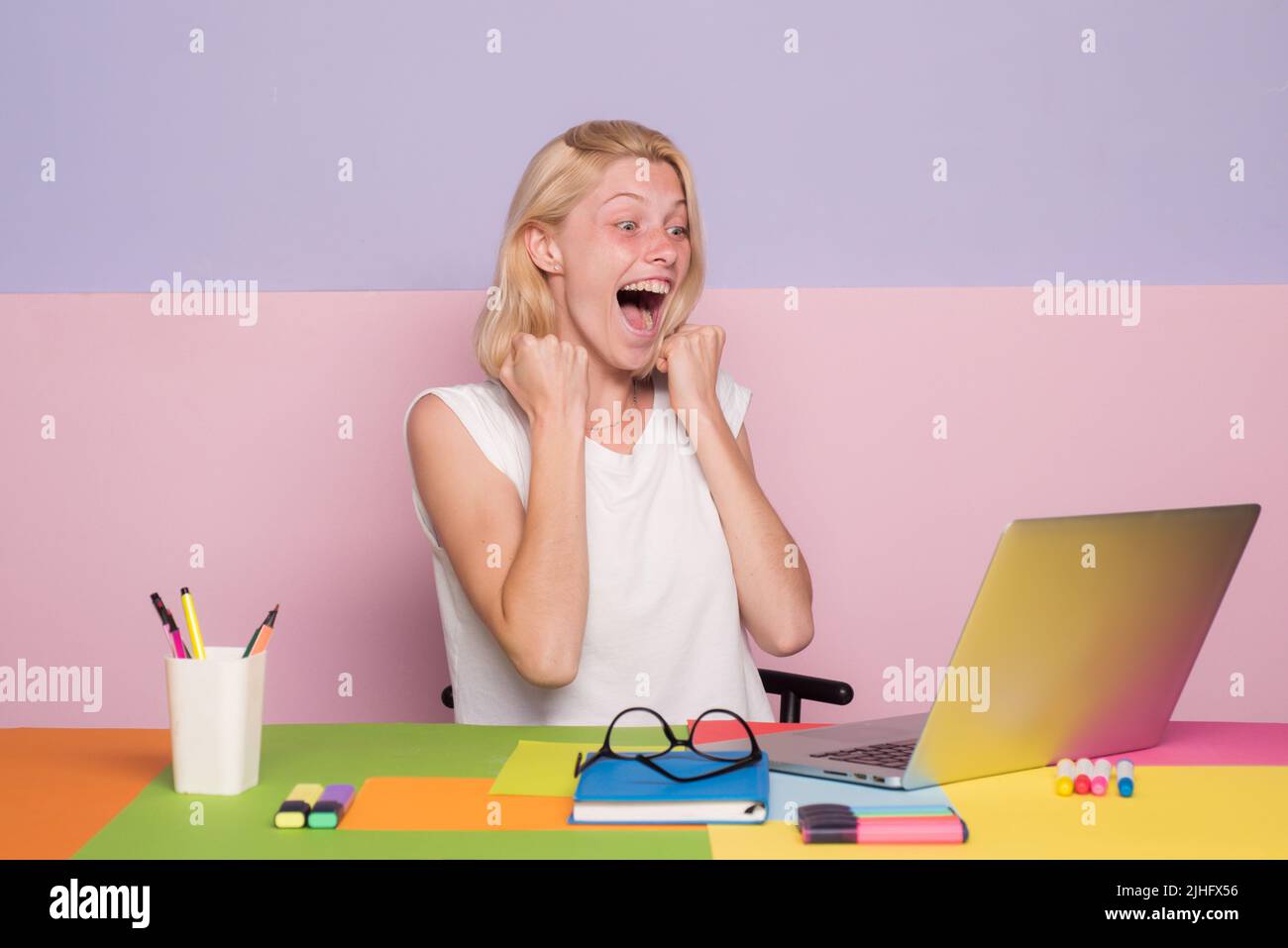 Female excited teacher use laptop at her desk marking students work ...
