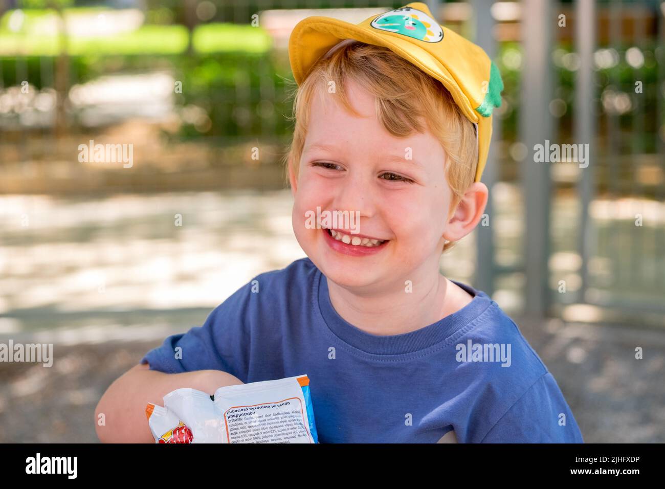 Cute little boy eating chips in the park Stock Photo