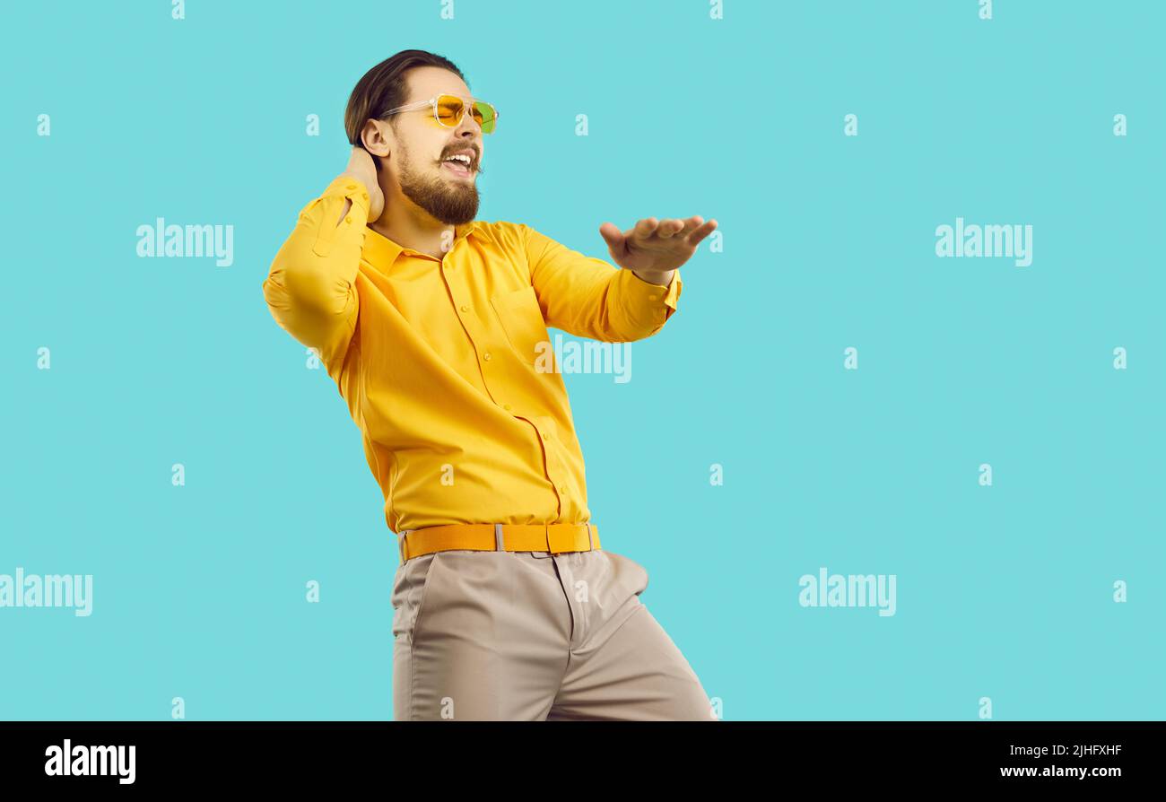 Cheerful cool stylish man partygoer having fun and dancing isolated on light blue background. Stock Photo