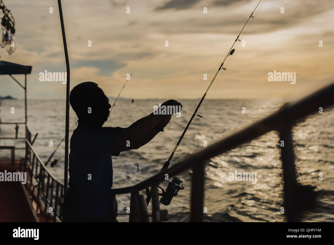Silhouette man fishing on the sea from the boat at sunset Stock Photo ...