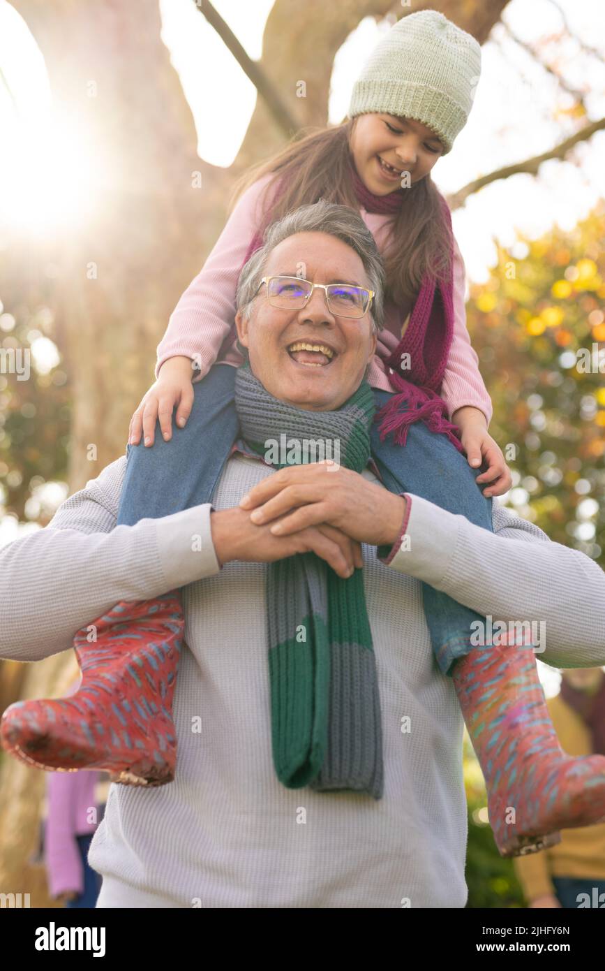 Vertical image of happy caucasian girl with grandfather in garden Stock Photo