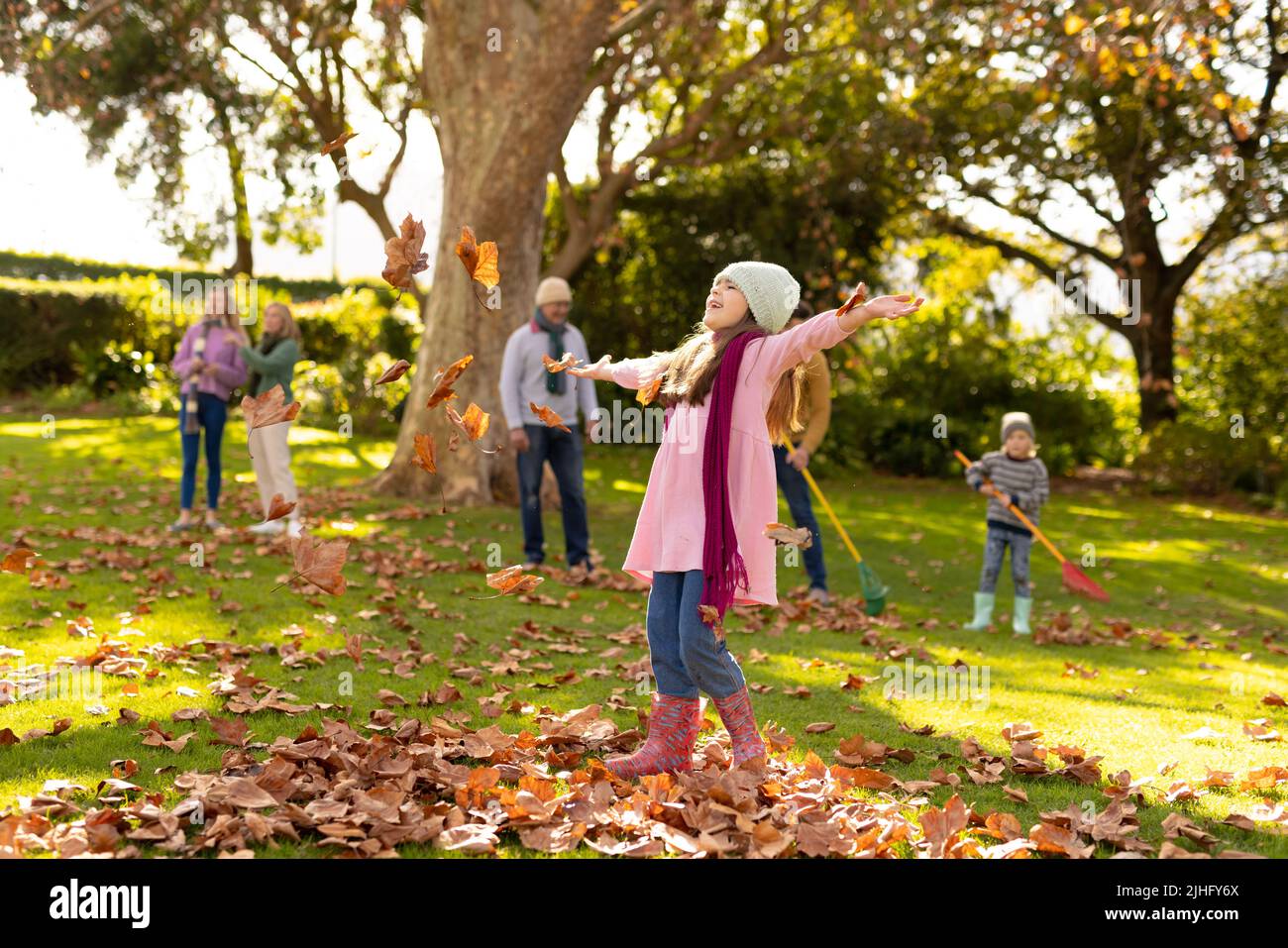 Image of happy multi generation caucasian family having fun with leaves in autumn garden Stock Photo