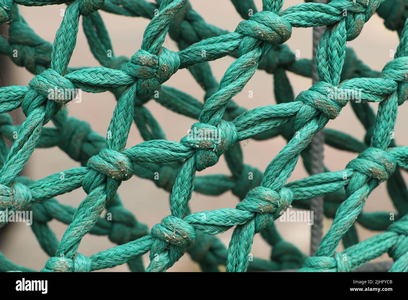 knots in turquoise colored fishing net rope close up Stock Photo