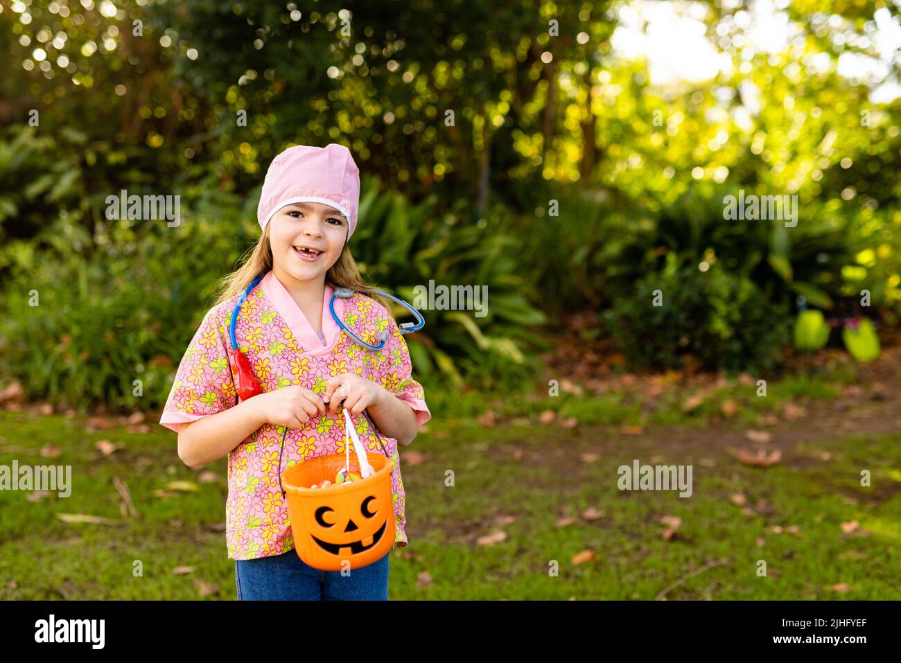 Image of happy caucasian girl in doctor costume in autumn garden Stock