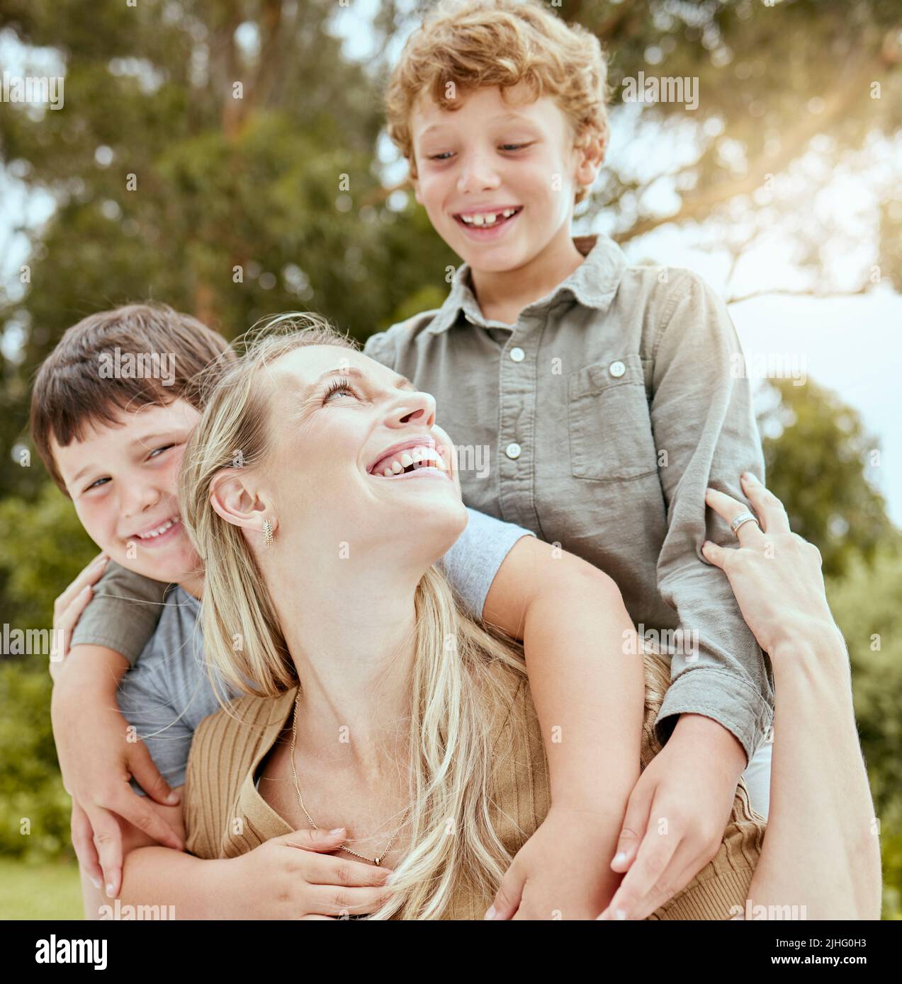 A happy caucasian single parent enjoying playing with her sons in the backyard. Smiling family of three having fun in a garden outside Stock Photo