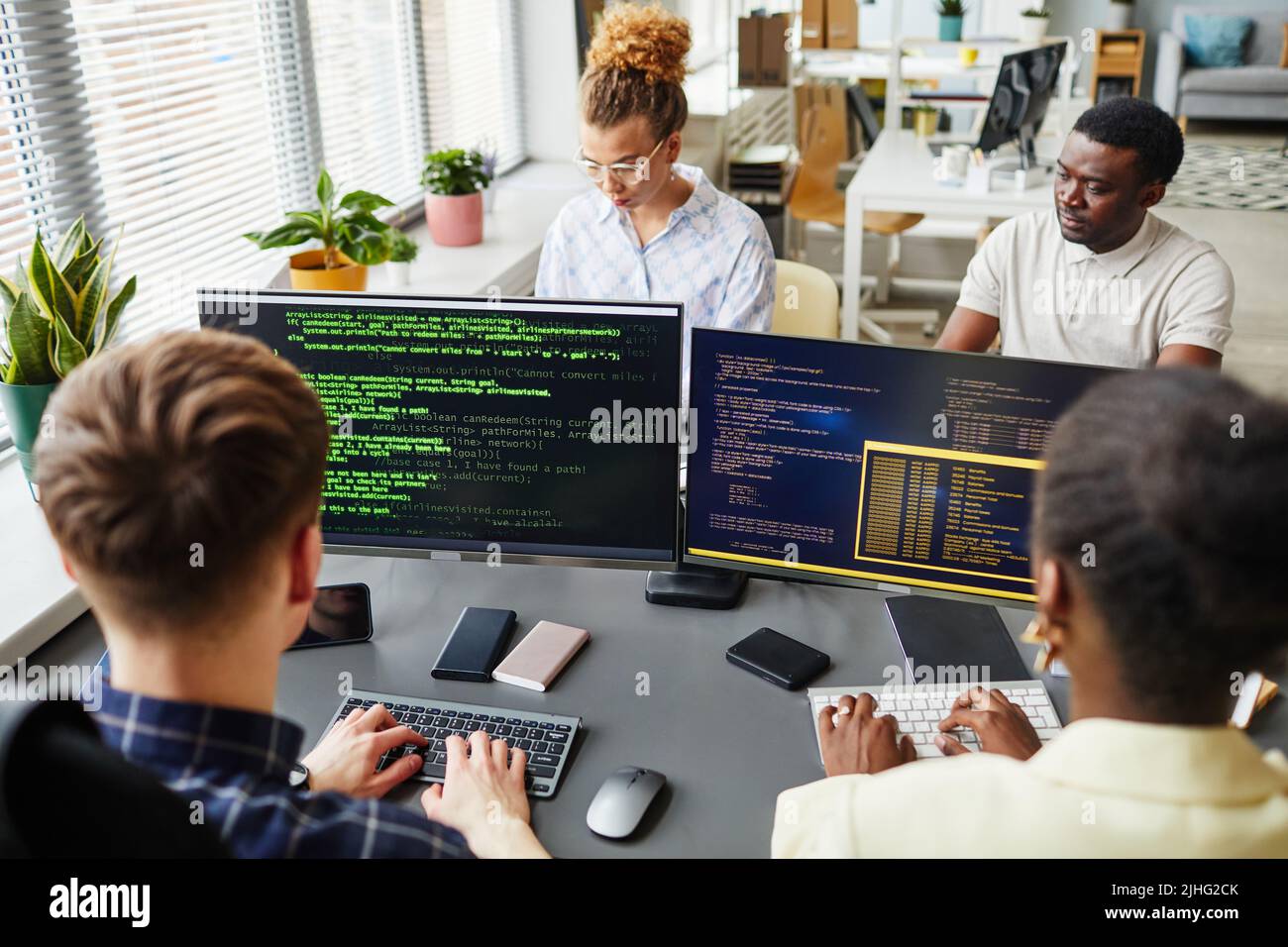 Group of software developers sitting at desk with computer monitors and working with codes of new software at office Stock Photo