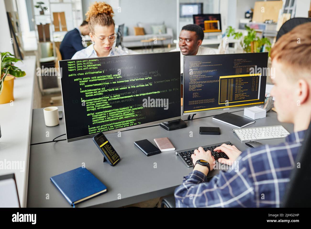 Multiethnic IT specialist working with program on monitors at office desk at IT company Stock Photo