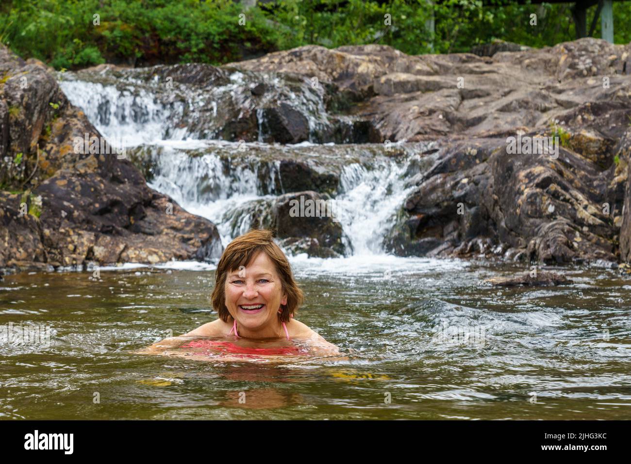 Woman swimming in a pool of water in Storforsen nature reserve, Älvsbyn county, Norrbotten province, Sweden Stock Photo