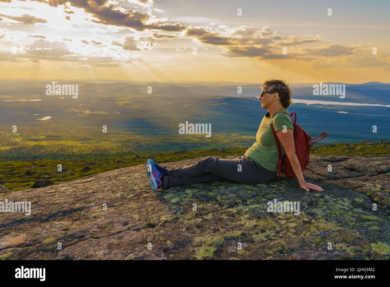 Woman sitting on mountain enjoying the view from Mount Dundret over Laponia, Gällivare county, Swedish Lapland, Sweden Stock Photo