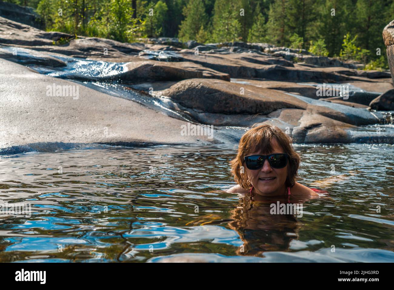 Woman swimming at Storforsen nature reserve, enjoying in summer time, Swedish Lapland, Sweden Stock Photo