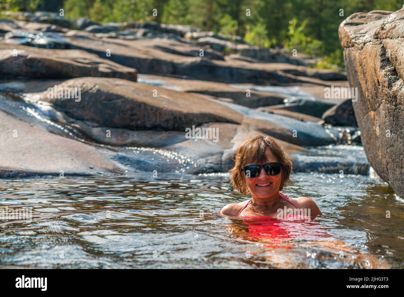Woman swimming at Storforsen nature reserve, enjoying in summer time, Swedish Lapland, Sweden Stock Photo